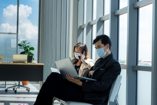 Businesspeople Sit In The Office Far Apart From Colleague In The Office To Prevent Virus Pandemic. Social Distancing New Normal Concept.