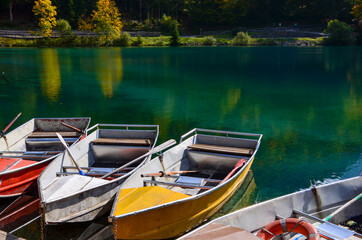 Colorful empty rowing boats on the lakes called Laghi di Fusine(Weissenfelser Seen) in Northern Italy in the triangle of Italy, Austria and Slovenia,Julian Alps,emerald green water, autumn landscape