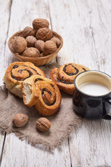 Fototapeta na wymiar Basket of homemade buns with jam, served on old wooden table with walnuts and cup of milk