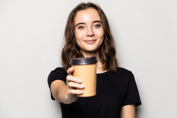 Young beautiful woman offers cup of coffee isolated on gray background