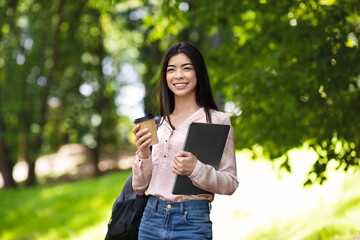 Fototapeta premium Millennial Asian Girl Walking Outdoors With Laptop And Coffee In Hands
