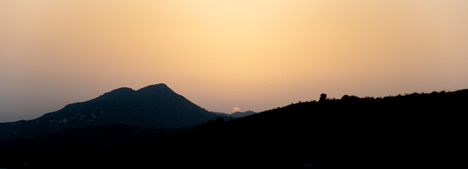 Fototapeta na wymiar Silhouette of mountains as dusk falls with the sun in the background at the orange hour