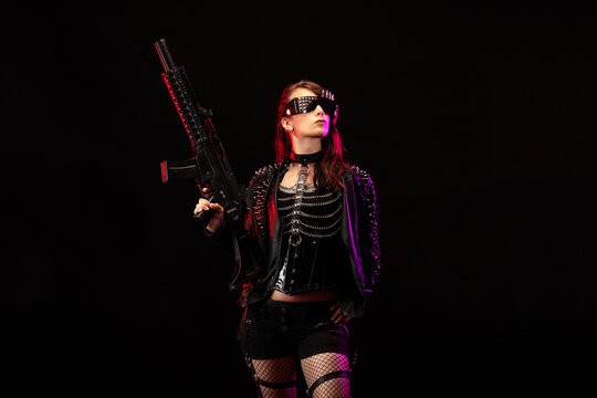 Young woman dressed in a studded leather jacket, a pair of cyberpunk glasses, holding an assault rifle in her hands