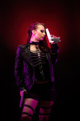 Young woman wearing a studded leather jacket, holding a revolver on her forehead	
