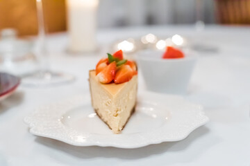 Fresh strawberry cheesecake on a ceramic plate on a white festive table