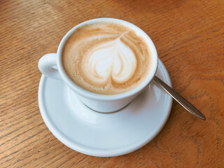 close up of cappuccino cup of coffee with cream designed in a sharp of heart isolated background.  