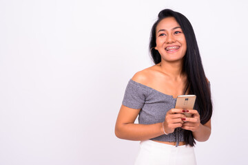 Portrait of happy young beautiful Asian woman using phone