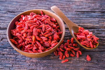 Goji berry chinese herb and superfood for wellness on a dark old wood background.
