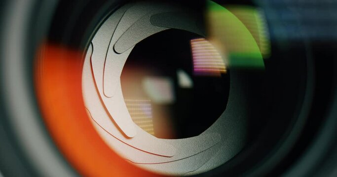 Extra macro of modern photo or video camera with a wide aperture diaphragm lens while opening for capturing with colorful blurred lights.