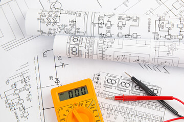 digital multimeter and paper electrical engineering drawings