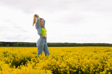 a blonde girl walks in a rapeseed field in the summer