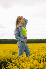 Fototapeta premium a blonde girl walks in a rapeseed field in the summer