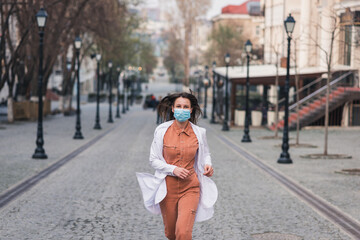 a brunette woman in orange clothes wearing white medical coat and a protective mask on her face