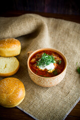 hot beetroot soup with sour cream, herbs and rolls in a ceramic bowl