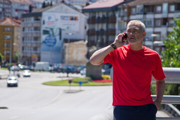 mature man doing sports and using mobile phone in the city