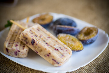 plum sweet homemade ice cream on a stick with slices of plum inside, in a plate