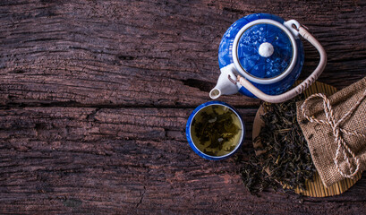 Dry green tea leaves teacup and hot ceramic teapots on wooden background. This is a very useful herbal medicine.