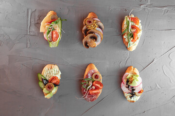 various beautiful bruschettas with vegetables, avocado, salami, cheese, tomatoes, guacamole, olives and radishes 