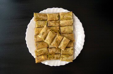 Traditional Turkish, Arabic, middle eastern baklava. Top view. Arabic baked sweets in white plate on dark wooden  table. Mini Baklawa 