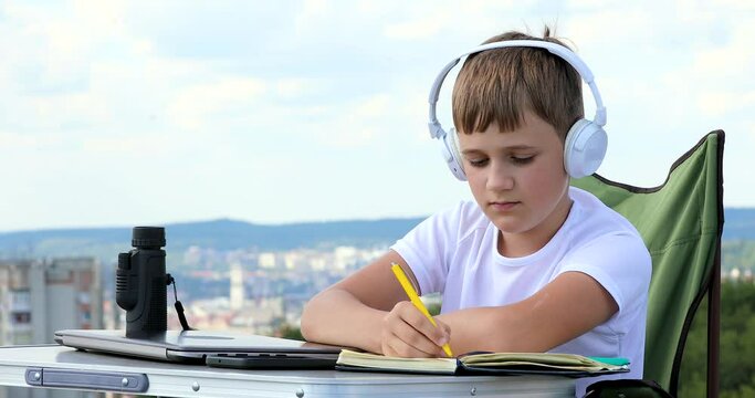 the boy learns, writes down ideas in a notebook and looks at monocular telescope