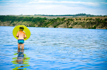 Little boy is swimming in the river with an inflatable circle