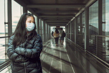 Asian Young Woman wearing face medical masked standing on boarding bridge on their way to the airplane. Protective equipment for passengers by plane transportation during covid19 virus pandemic.