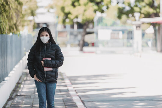 High School Teenage Students Walking To School Alone While Wearing Face Masks As Protection Against Infectious Diseases Outdoors During Coronavirus Pandemic. New Normal Life Of Student Concept.