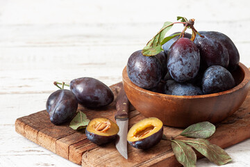 Fresh plums on white wooden table.