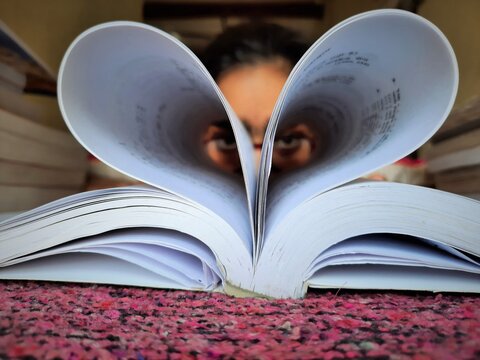 girl making heart shape of book pages and showing love on book lovers day