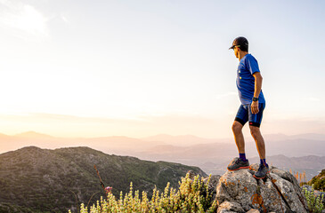 Male person meeting dawn on top of the mountain. Panoramic view of beautiful valley in front of him.