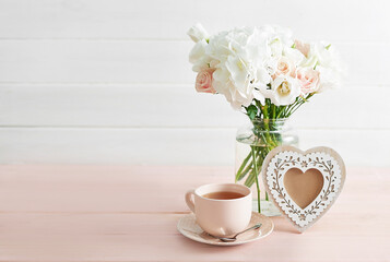 Bouquet of roses, eustomas and hydrangeas on table. Cup of tea and photo frame. Greeting card for mothers day. Cozy good morning. Happy Birthday. Romantic breakfast. Flowers composition for Valentine