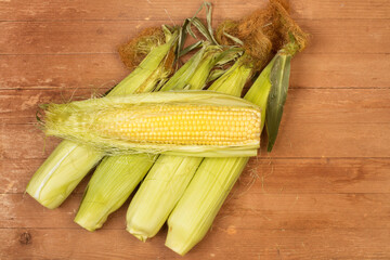 Mazorcas de maíz natural y crudo sobre un fondo de madera rústico. Vista superior y de cerca