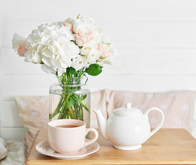 Breakfast in bed in hotel room. Accommodation. Breakfast in bed with tea cup and flowers on bed background top view. Copy Space. Romantic valentine's day breakfast. Cozy morning. Happy Mother's Day