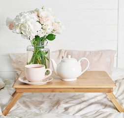 Breakfast in bed in hotel room. Accommodation. Breakfast in bed with tea cup and flowers on bed background top view. Copy Space. Romantic valentine's day breakfast. Cozy morning. Happy Mother's Day