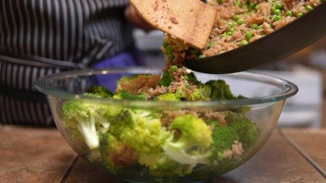 Adding fried rice to stir fry broccoli for a delicious meal - slow motion