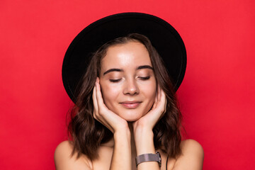 Young pretty girl with floppy hat isolated over red background