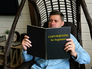 Copywriting for beginners. A man is reading a guide at home.