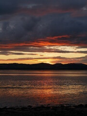 sunset over the hills and water, dramatic grey clouds