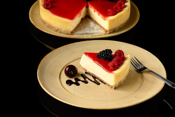 a slice of red fruit pie on a ceramic plate photographed in a black background