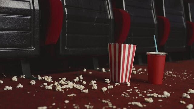 Pan shot of cinema hall with no people, empty seats and popcorn scattered all over
