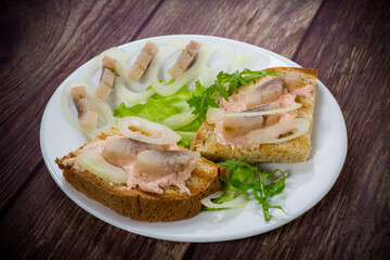 sandwich with salad, herring and herbs with onions in a plate