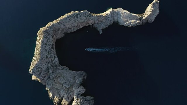 Drone footage of boat crossing an island one by secret cave, close to Ibiza island.