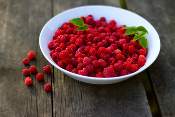 Red fresh raspberries with green leaves in a white misk on a wooden background with copy space.
Healthy snack. Summer healthy food concept. Healthy organic sweet fruits.