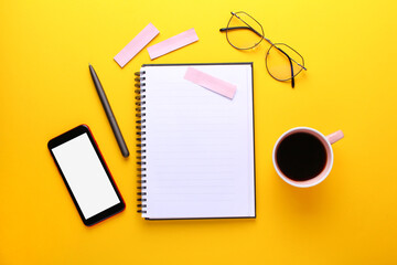 Notebook, eye glasses, cup of cofee, pen , smartphone, stickers on yellow background.Education and work concept, top view shot of workplace, flat lay, copy space.