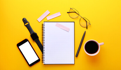 Notebook, eye glasses, cup of cofee, pen ,smart watch, mobile phone, stickers on yellow background.Education and work concept, top view shot of workplace, flat lay, copy space.