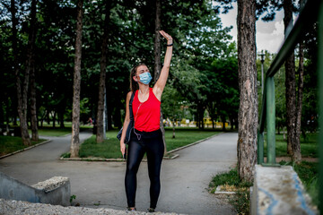 Young  Caucasian woman with protective face mask on her way to training in a public park.