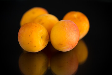small handful of ripe apricots on black background
