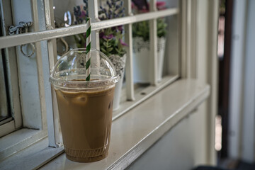 Ice coffee in a transparent cup placed in a lattice window
