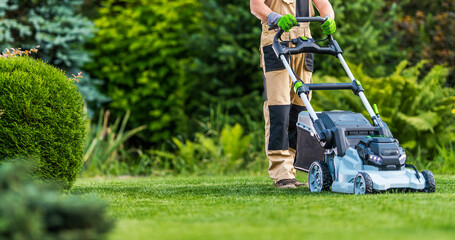 Gardener Trimming Grass Lawn Using Electric Cordless Mower - obrazy, fototapety, plakaty