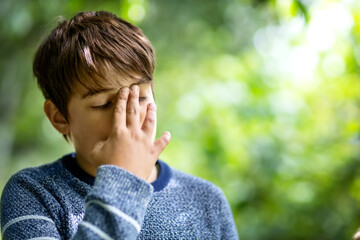 child with headache. Upset young boy outdoors